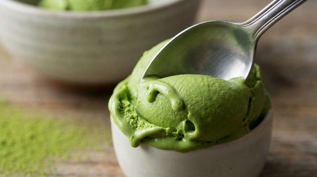 A silver spoon scooping through a bowl of ultra creamy vibrant green matcha ice cream